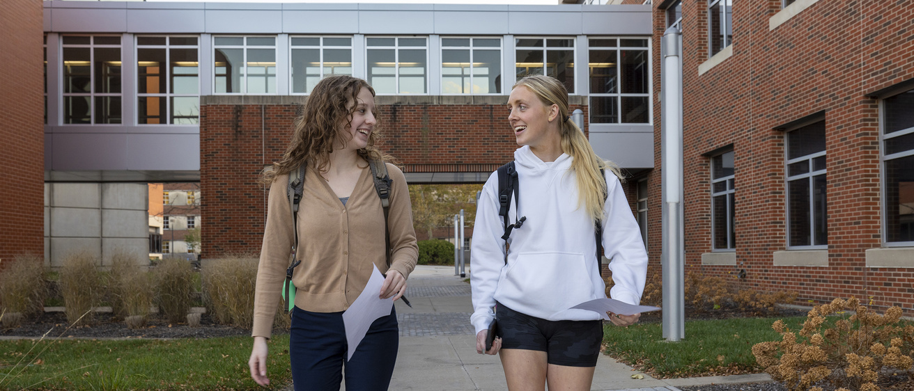 Two students talking as they walk outside