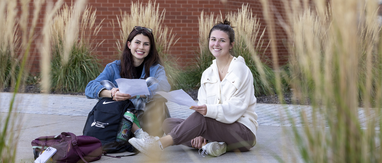 Two female students sitting outside