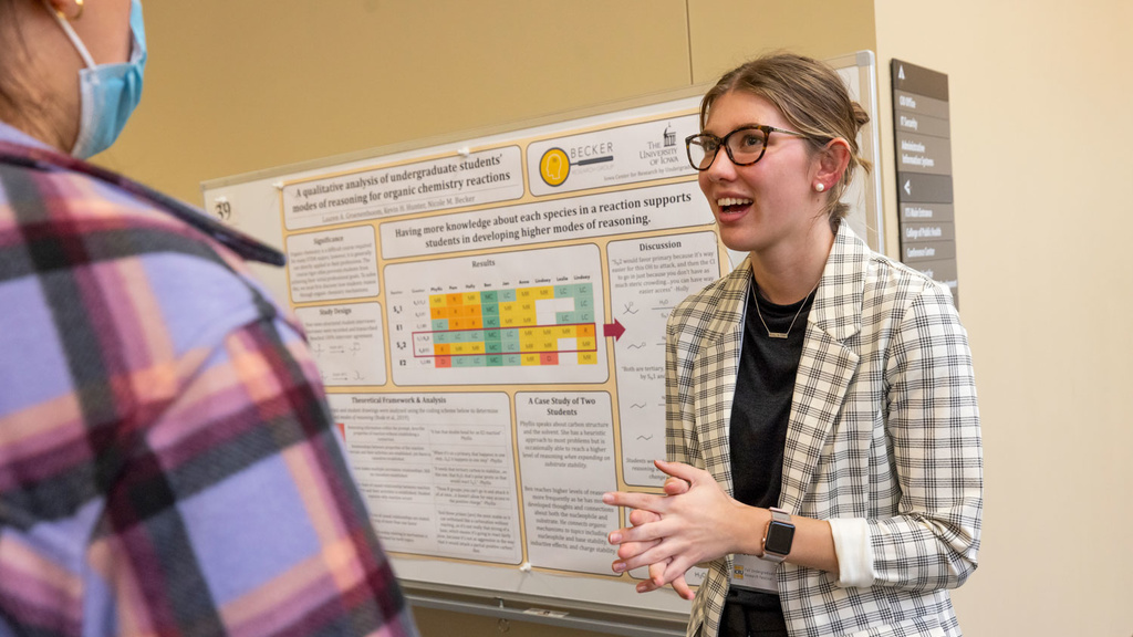 Woman presents a poster of her research